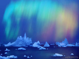 A colorful sky with some ice bergs in the water