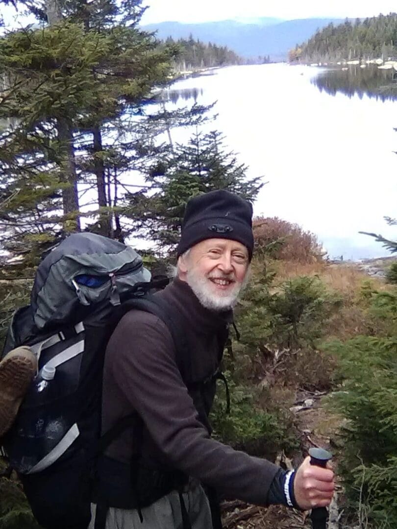 Smiling hiker with backpack by a lake.