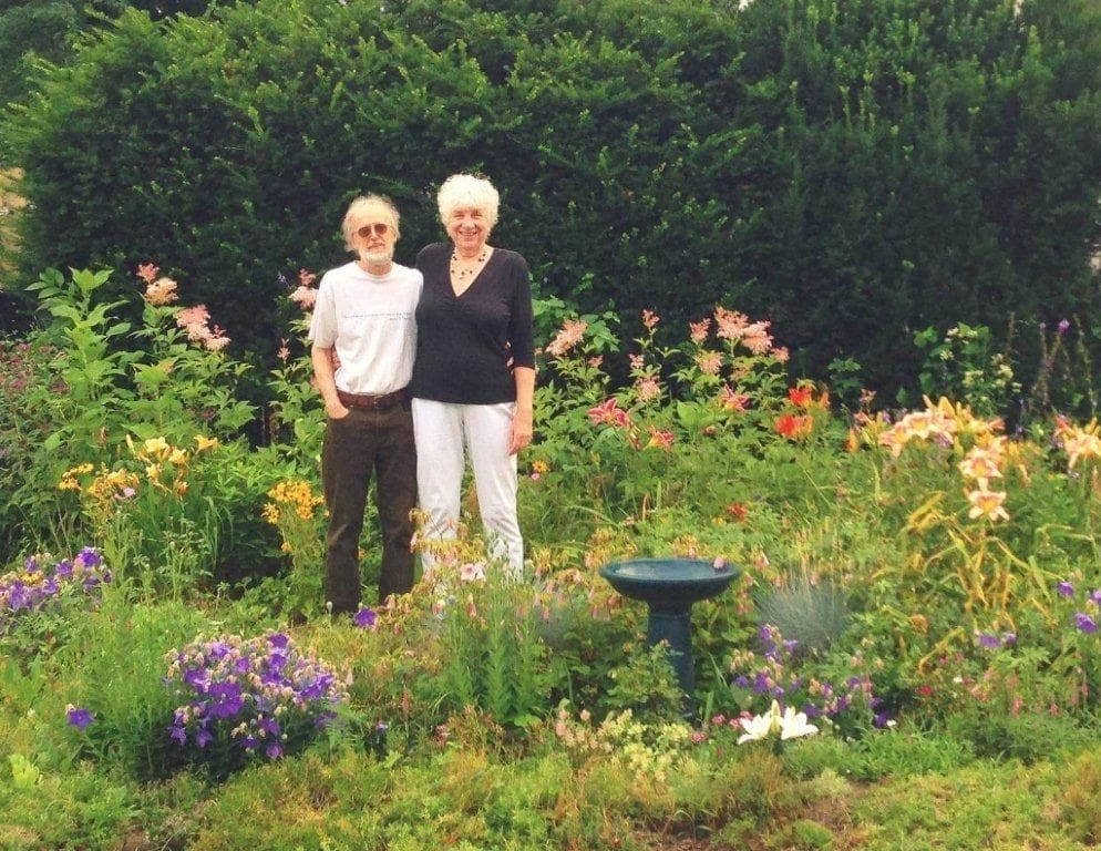 Couple standing in a vibrant flower garden.