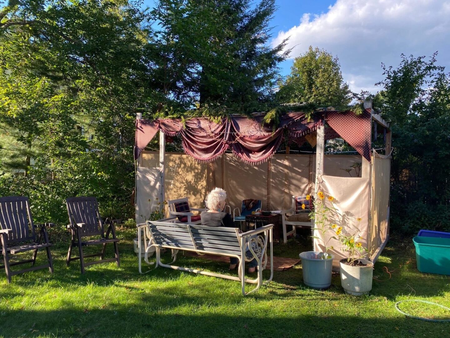 A gazebo with curtains and a bench in the middle of a yard.