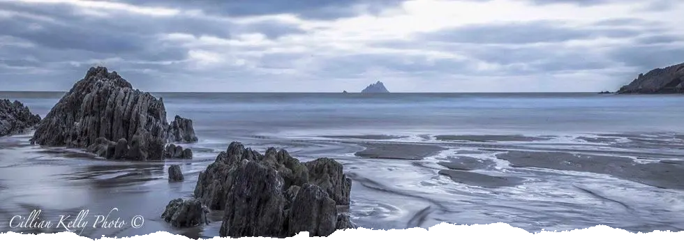 Serene coastal scene with rocks and island.