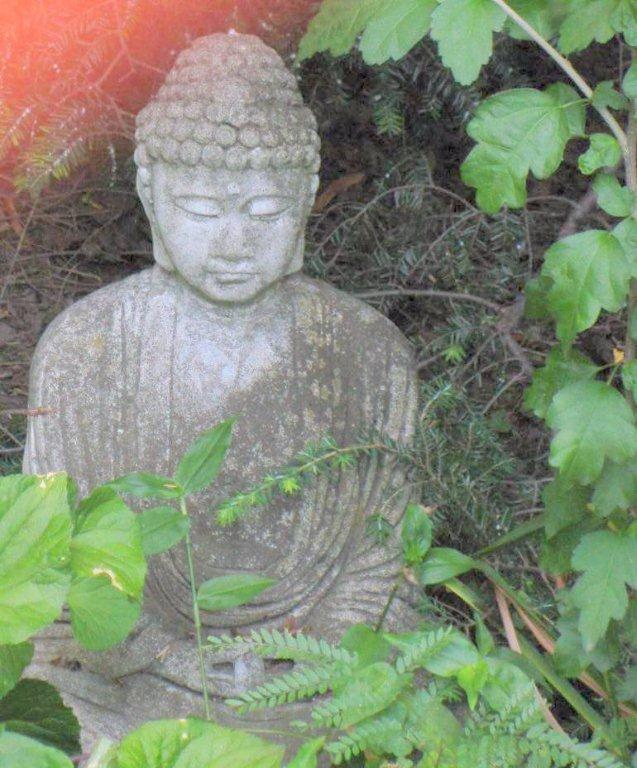 A statue of buddha in the middle of some bushes