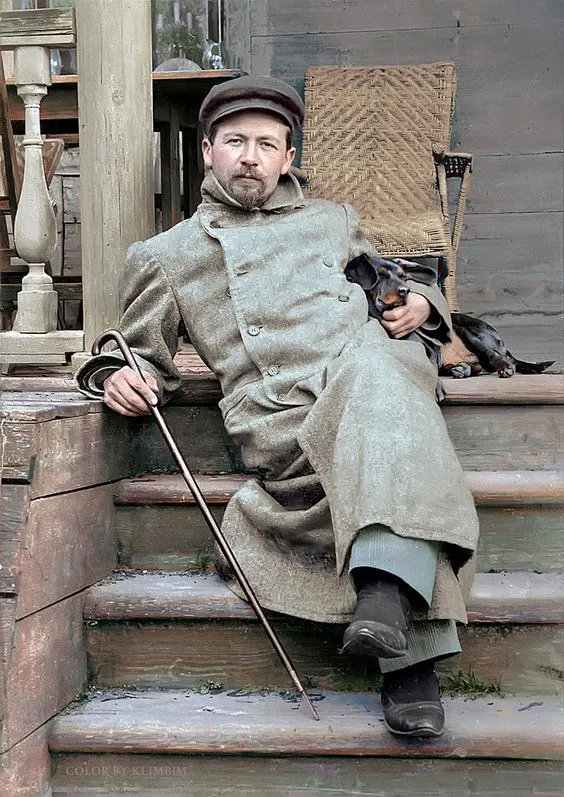 Man in coat with dachshund on steps.