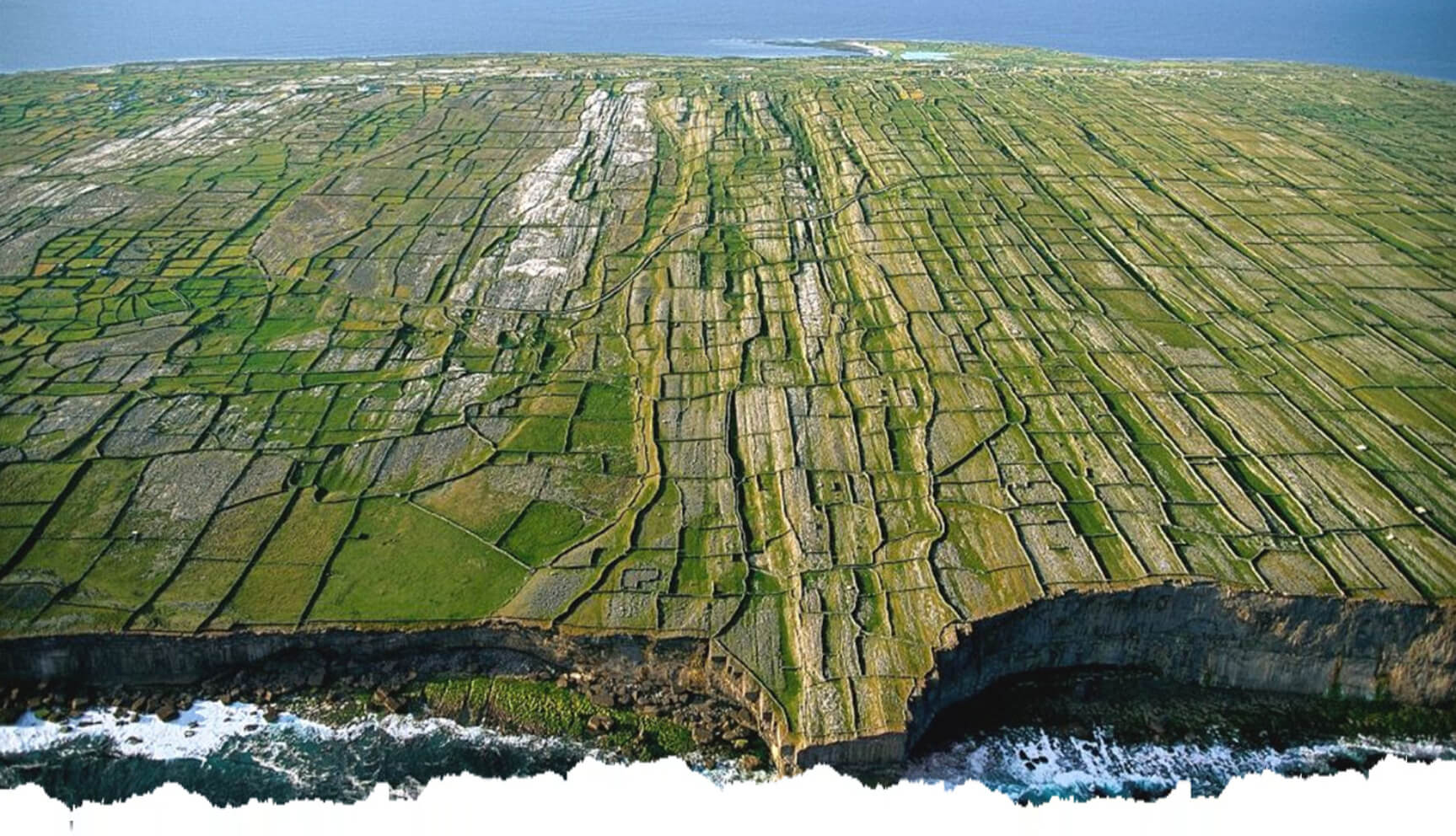 A large field of grass on the side of a cliff.